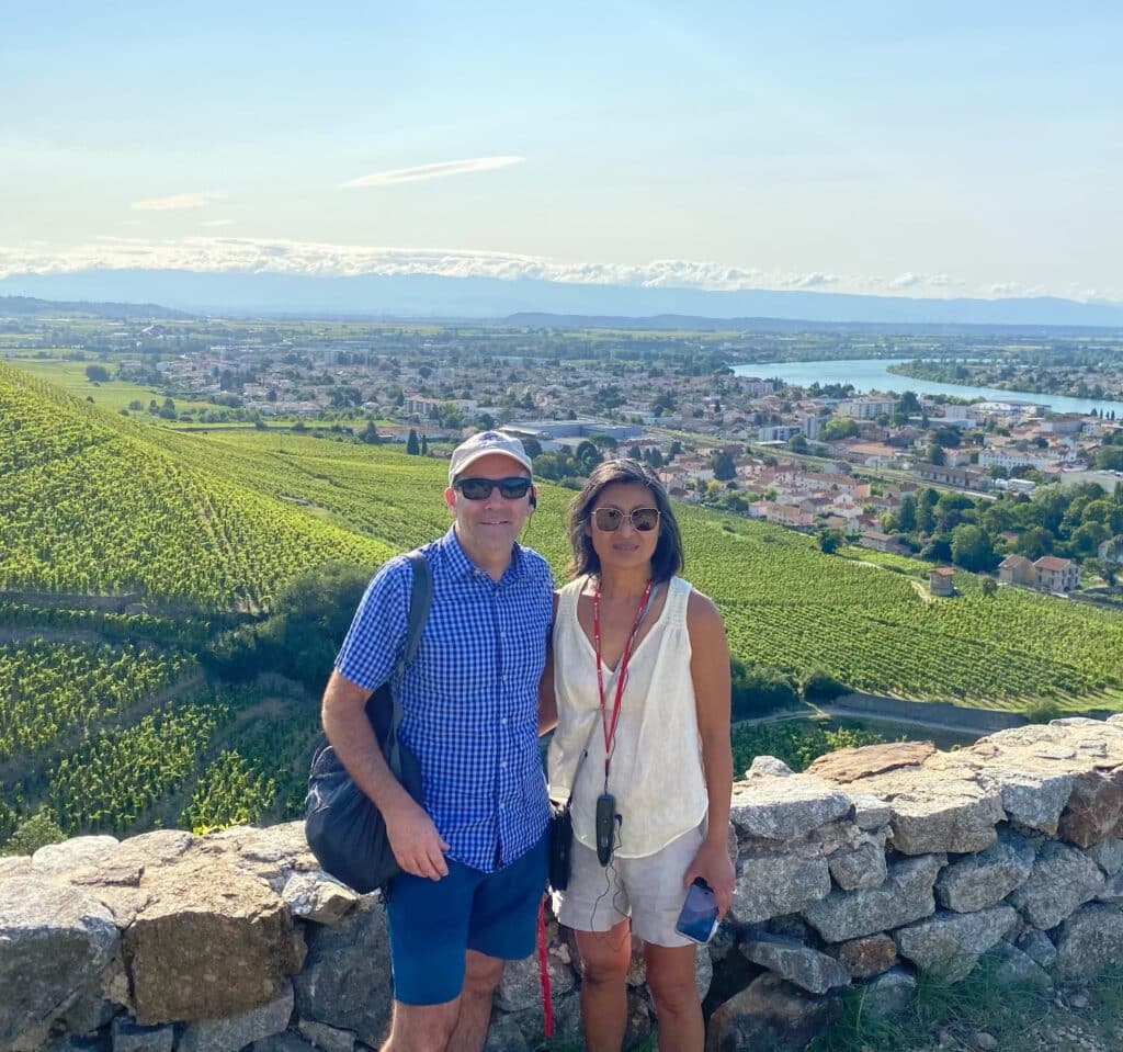 Couple pose in front of stone wall and beautiful landscape on sunny day
